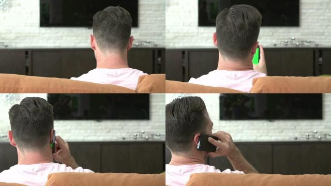 男子坐在沙发上接听手机的后视图