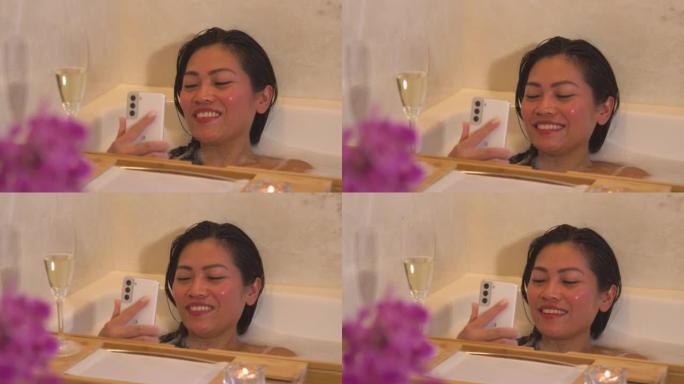 特写: 泡泡浴中迷人的年轻女子通过智能手机进行视频聊天