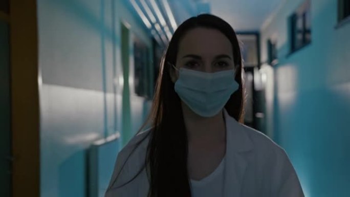 一名年轻女医生在医院走廊上摘下口罩的SLO MO肖像