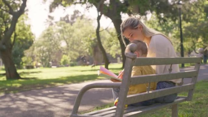 家庭，孩子和公园长椅，而母子俩坐在一起看书，在夏天放松，学习和享受大自然的乐趣。女人和男孩分享纽带和