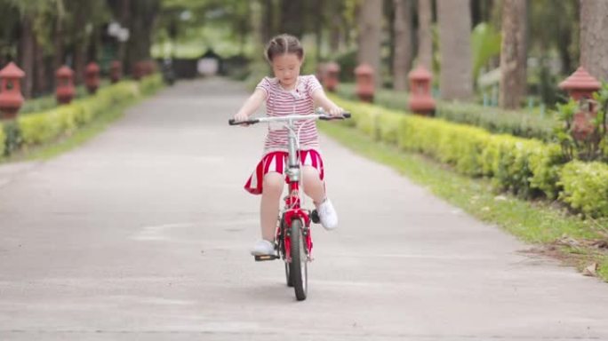 快乐亚洲女孩骑自行车在公园