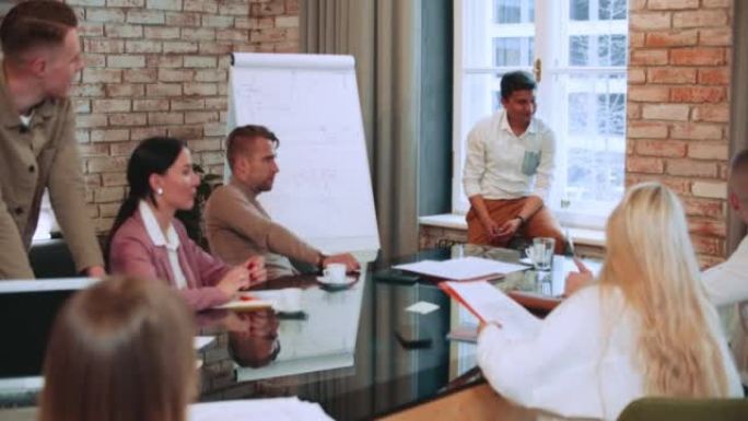 商业教练自信的印度男性企业家，销售专家演讲，与办公室餐桌上的一群经理分享