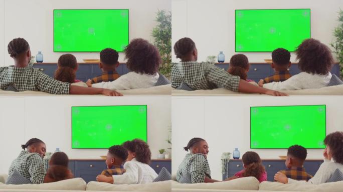家庭坐在沙发上的后视图在家里的绿屏电视上看恐怖电影