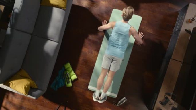 顶视图运动: 男人在家里的垫子上做俯卧撑运动。肌肉发达，身体健康，非常强壮的运动员在他的公寓里锻炼。