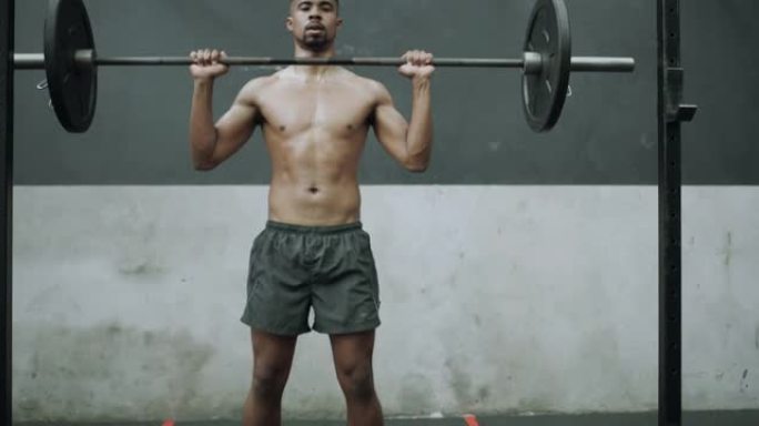 4k视频片段，一个肌肉发达的年轻人在健身房用杠铃进行头顶按压