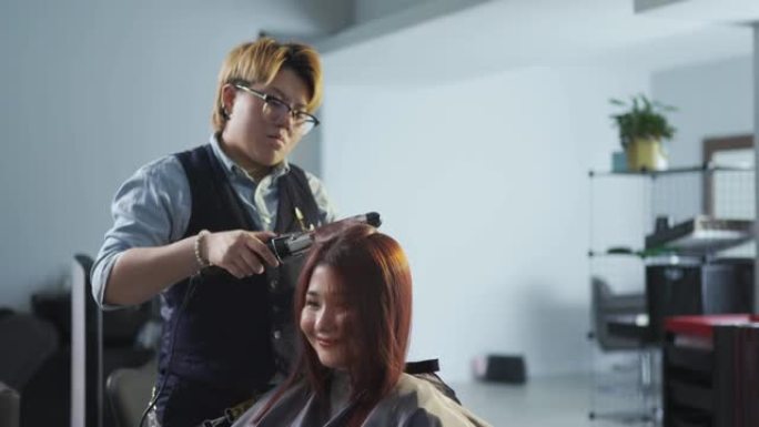 亚洲中国发型师女性卷发为她的顾客在发廊