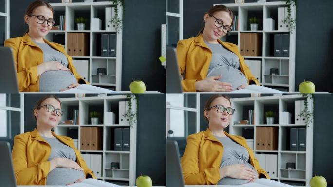 好看的孕妇抚摸肚子表达对工作场所婴儿的关心和爱