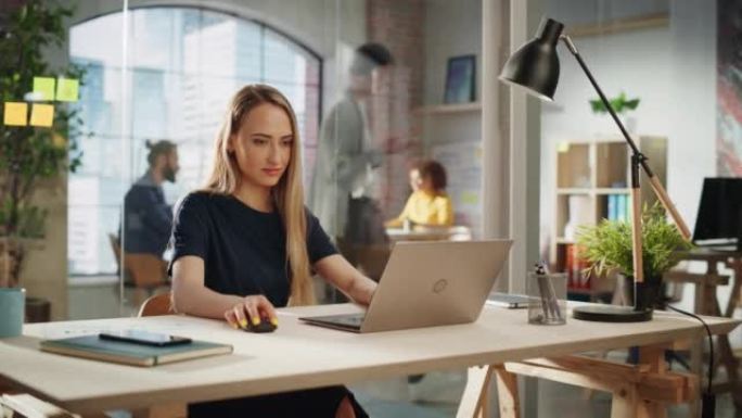自信的女经理坐在创意机构的办公桌前，致力于为客户实施现代商业战略。创意专家在笔记本电脑上编写公司项目
