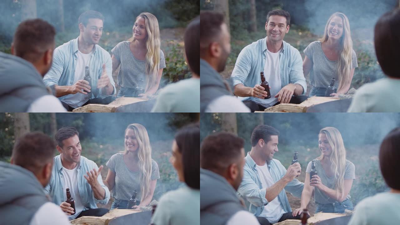 一群朋友露营坐在火旁做饭，一起喝啤酒