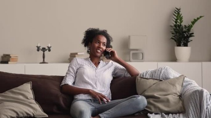 非洲妇女在沙发上放松与朋友的电话交谈