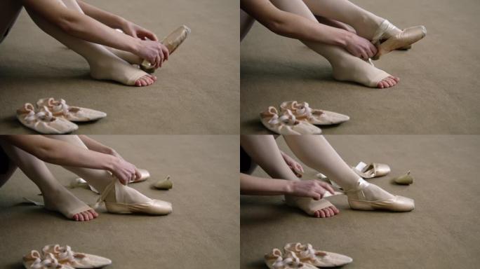 芭蕾舞女演员坐在地板上，穿上脚鞋