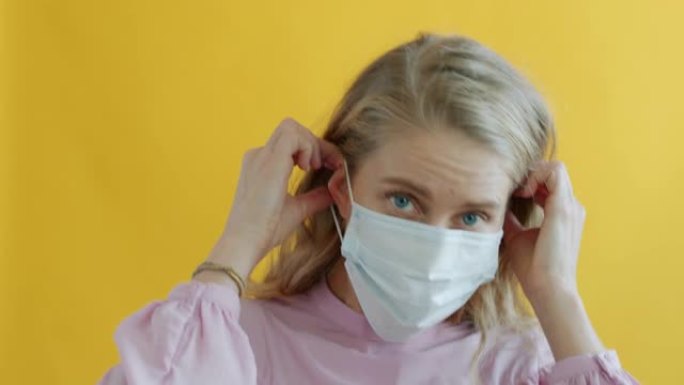 新型冠状病毒肺炎大流行期间欢快的年轻女子跳舞和戴上医用口罩的肖像