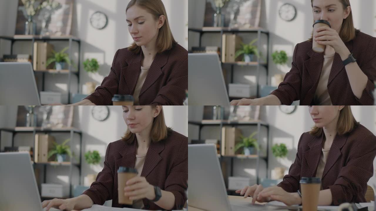 女性上班族在工作场所使用笔记本电脑工作和喝酒去喝咖啡