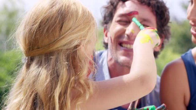 一个小女孩和她的父母在户外一起玩油漆的4k视频片段