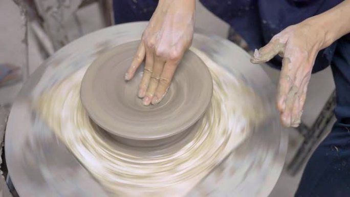 一位亚洲女性在她的陶器车间里用轮子做陶瓷。