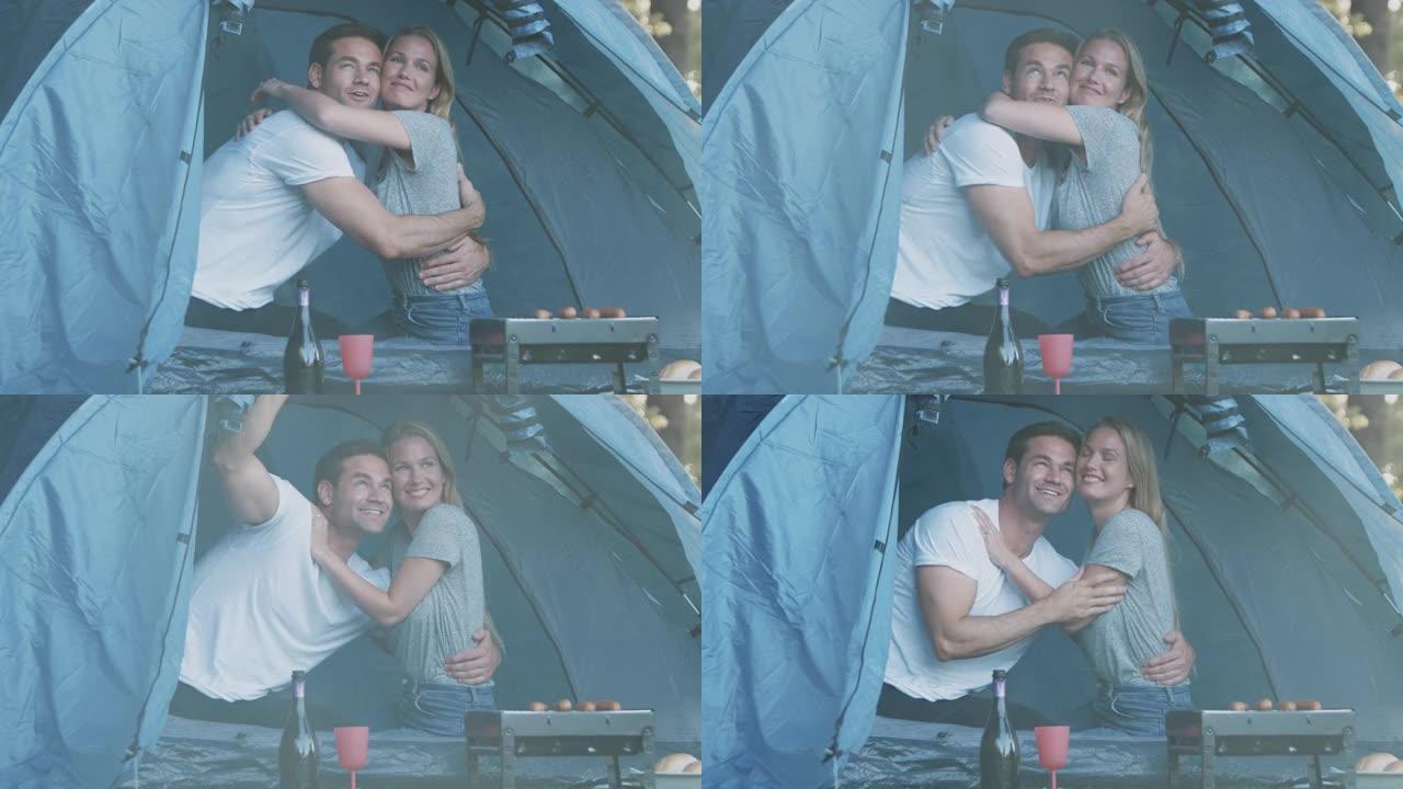 情侣们在雨中露营的帐篷里坐着烧烤香肠