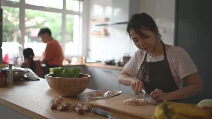 亚洲华人母亲与家人在厨房柜台做饭准备食物
