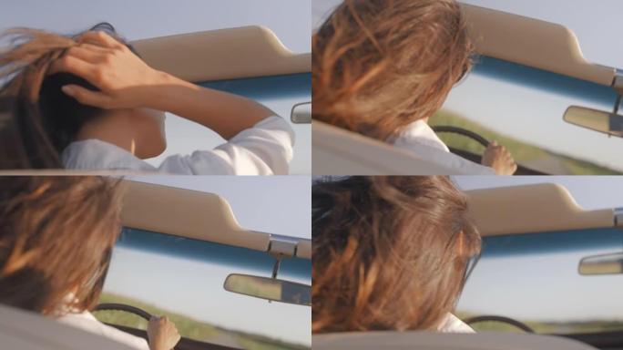 SLO MO年轻女子在日落时驾驶敞篷车时将头发塞在耳朵后面