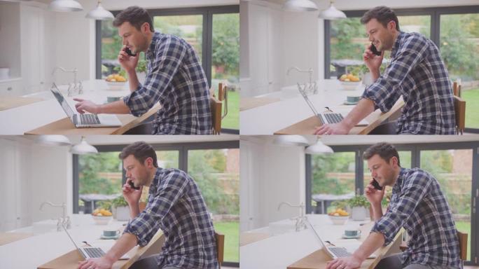 男子在家工作时在厨房柜台上使用笔记本电脑，同时在手机上聊天