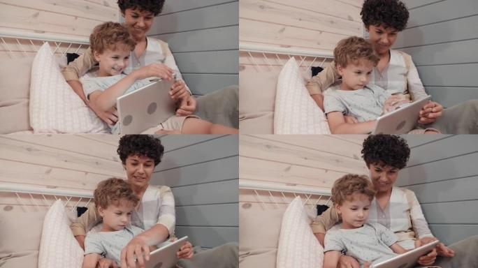 年轻的母亲和可爱的男孩使用平板电脑