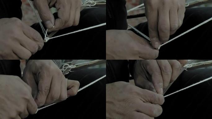 一个穷人的手在用木箱手工制作风筝时系绳子。特写。