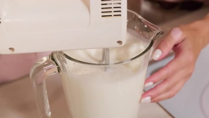 用手动搅拌器搅打牛奶
