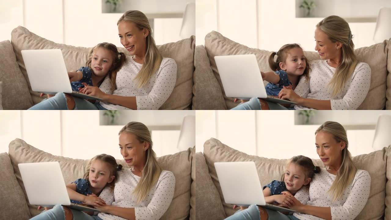 女人花时间和女儿一起用笔记本电脑在沙发上放松
