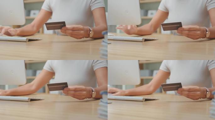 4k视频片段，一名妇女在计算机上打字时拿着信用卡