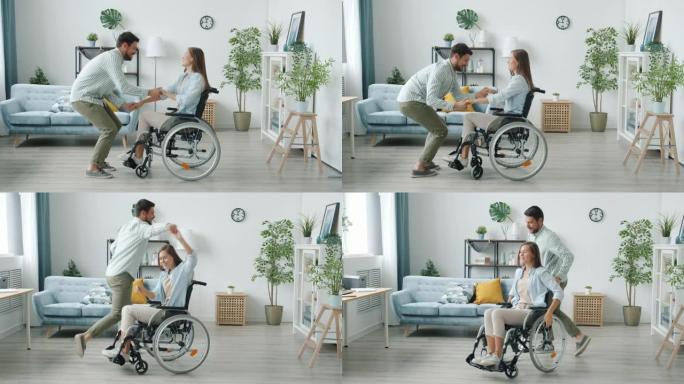 坐在轮椅上的年轻残疾妇女的慢动作和快乐的丈夫在家里跳舞