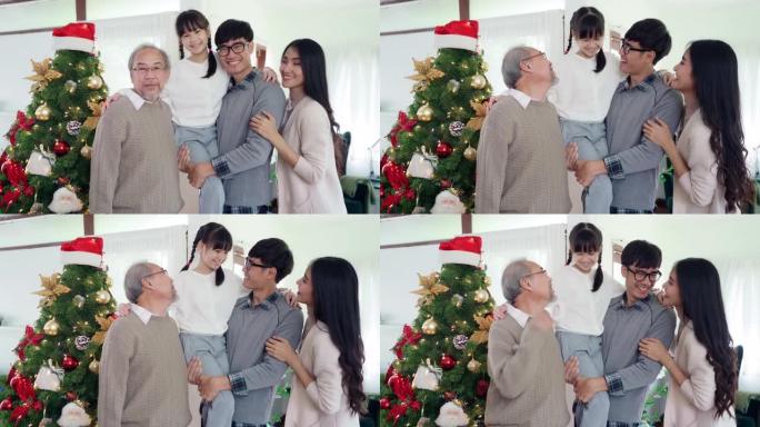 4K UHD手持肖像微笑多代亚洲幸福家庭站在一起，装饰完装饰品后与圣诞树。