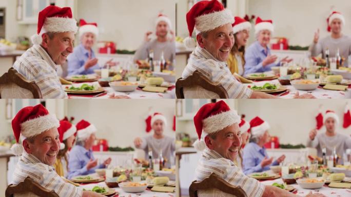 坐在餐桌上享受伦时戴着圣诞老人帽子的高加索老人的肖像