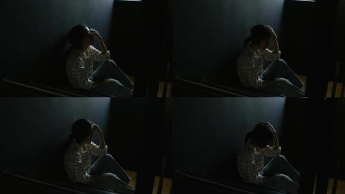 一个悲伤的年轻女孩坐在黑暗中的剪影