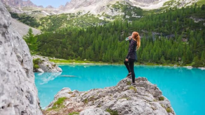 适合女人在美丽的碧绿湖水前的山石上喝水