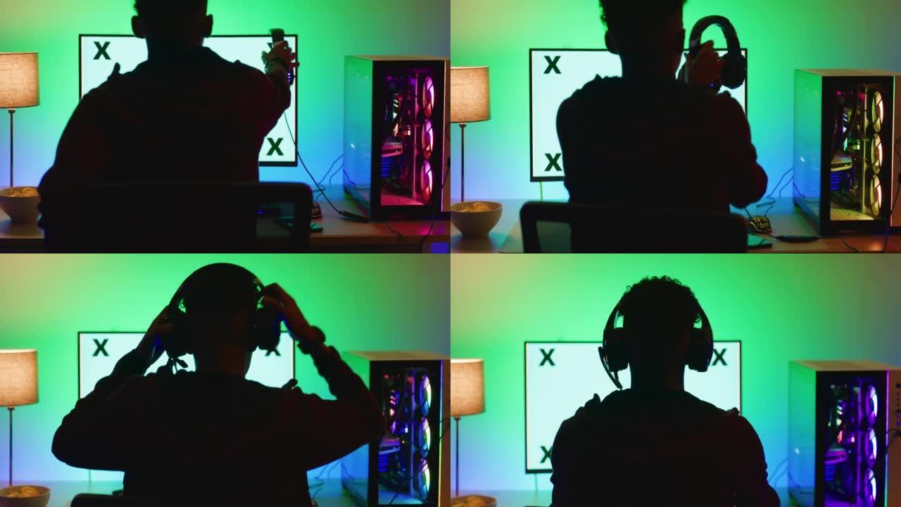 一个戴着耳机并准备玩pc游戏的电脑游戏玩家的后视图。十几岁的男孩坐在黑暗的房间里使用空白的桌面显示器