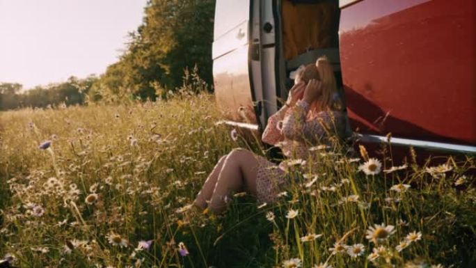 DS女人在停在草地上的露营者的头发上放一朵花