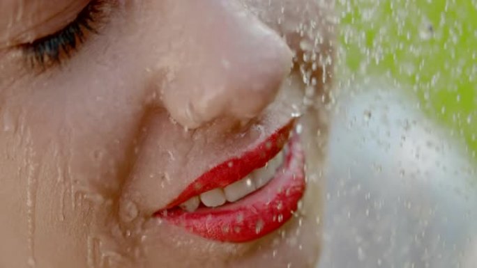 超级SLO MO水滴落在年轻女子脸上，带有强烈红色的唇膏