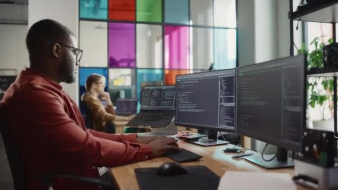 非裔美国人在台式计算机上编写代码，设置了多个显示器，并在Creative Office中使用笔记本电