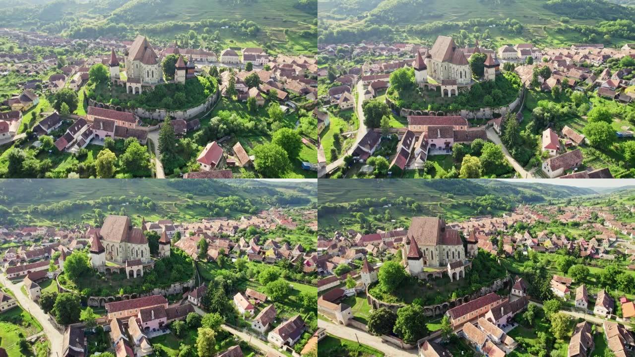 在罗马尼亚特兰西瓦尼亚的比尔坦村的老比尔坦强化教堂周围飞行。日落时老撒克逊村庄比尔坦的鸟瞰图。教堂周