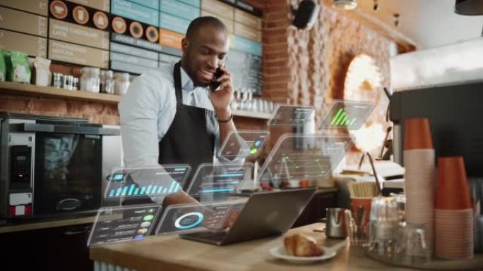 非裔美国人咖啡店老板正在舒适的咖啡馆里用电脑和电话聊天。餐厅经理笔记本电脑弹出的增强现实图标: 小企