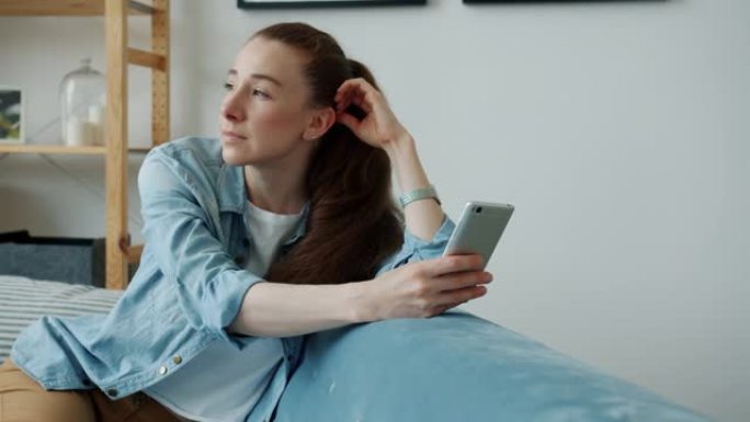 年轻女子在现代公寓触摸屏上的智能手机上享受社交媒体