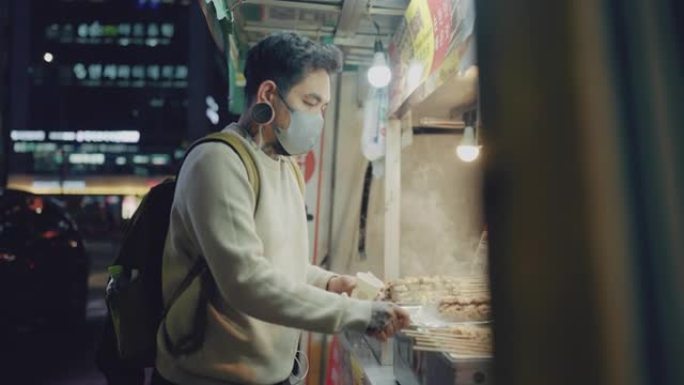 年轻人游客在首尔的一条步行街上吃典型的韩国街头美食。