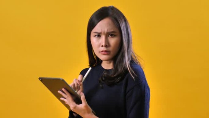 严肃的女人在黄色背景上使用数字平板电脑