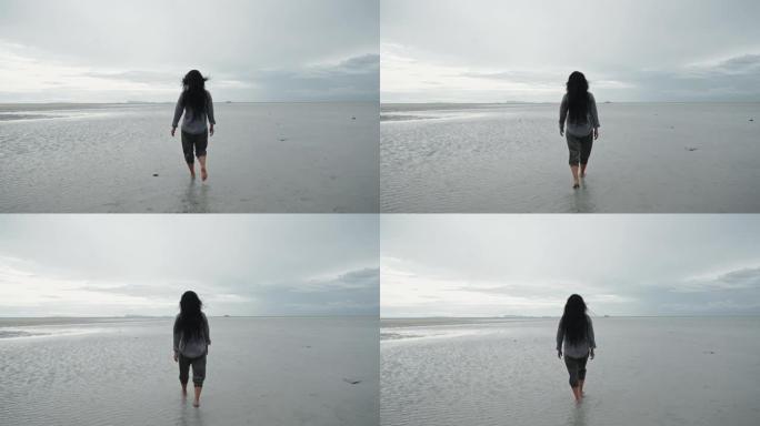 孤独的女人走在沙滩上