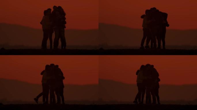 黄昏时在山上拥抱的剪影中的SLO MO LS家族