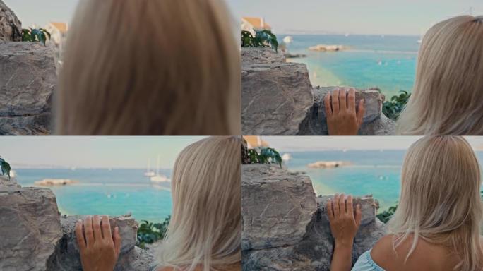SLO MO女人从海滩上方的石墙欣赏美景