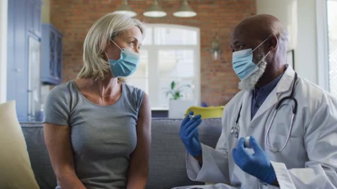 快乐的高级多元化妇女和医生戴着口罩在客厅坐在沙发上，接种疫苗