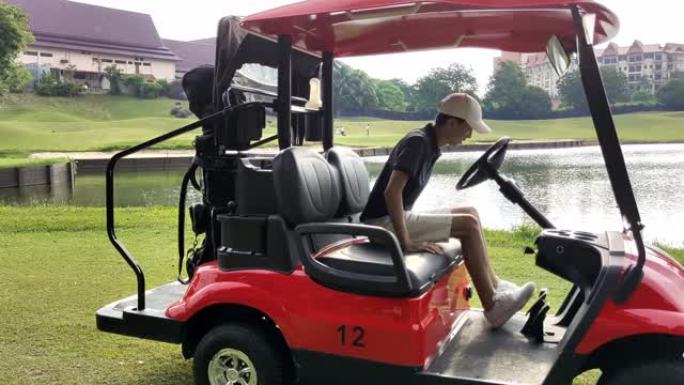 一个亚洲华裔少年男孩从高尔夫球车上提着高尔夫球袋，走到发球台开始打高尔夫球