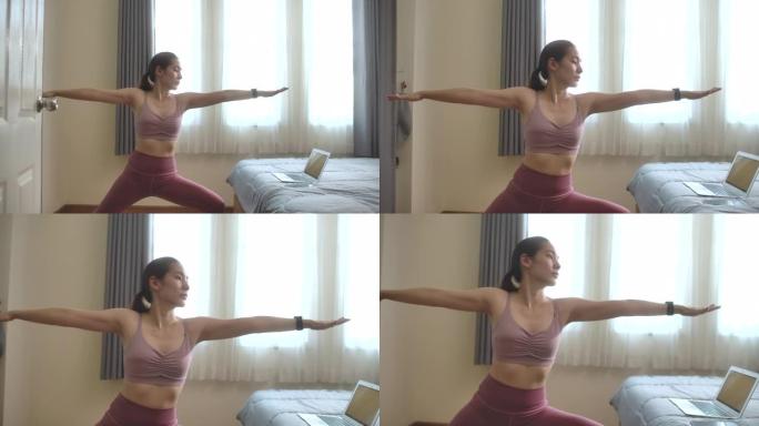 亚洲女性在家用笔记本电脑做瑜伽运动