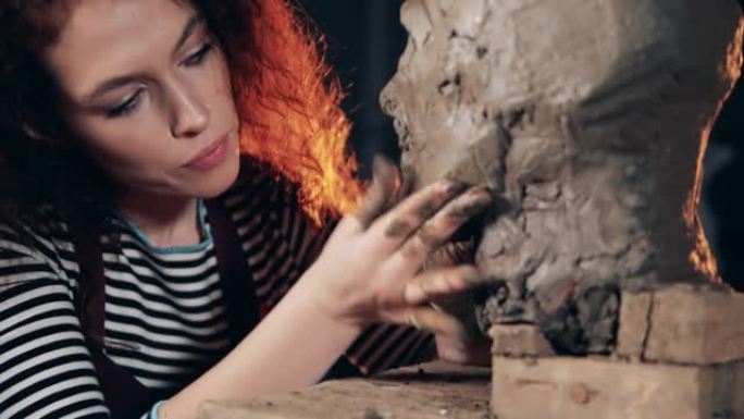 一个女人正在揉捏泥塑以创造面部特征