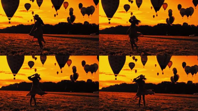 WS的剪影，一个无忧无虑的女人在野外旋转，在日落时天空中有热气球